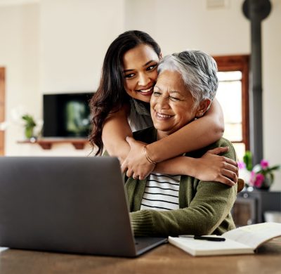 Cropped shot of an attractive young woman hugging her grandmother before helping her with her finances on a laptop